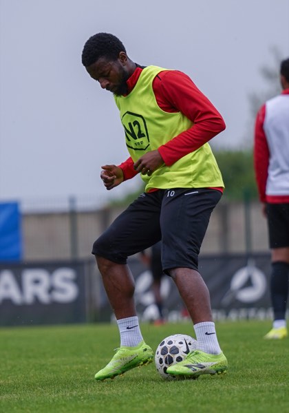 Joueur en chasuble jaune contrôlant le ballon à l'entraînement