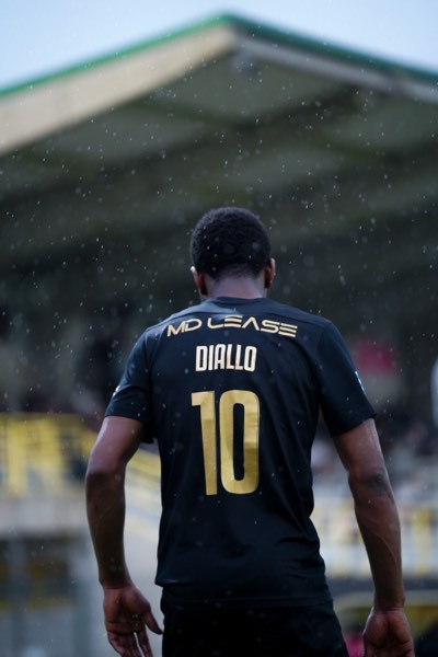 Joueur de dos sous la pluie, maillot noir floqué Diallo numéro 10