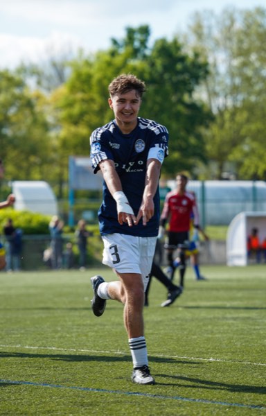 Joueur souriant en course, maillot bleu marine numéro 3