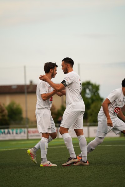 Deux joueurs en blanc se félicitant après un but