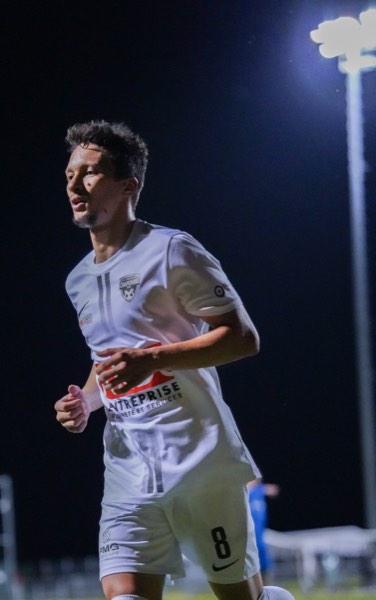 Joueur en maillot blanc courant sous les projecteurs de nuit
