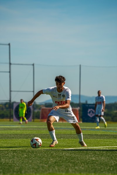 Joueur frappant le ballon, maillot blanc floqué ARD, lumière rasante