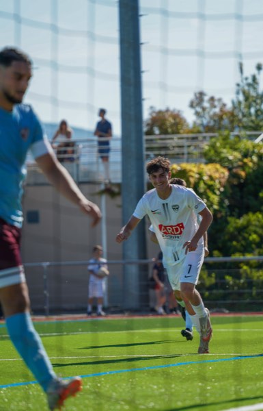 Joueur souriant célébrant un but à travers un filet